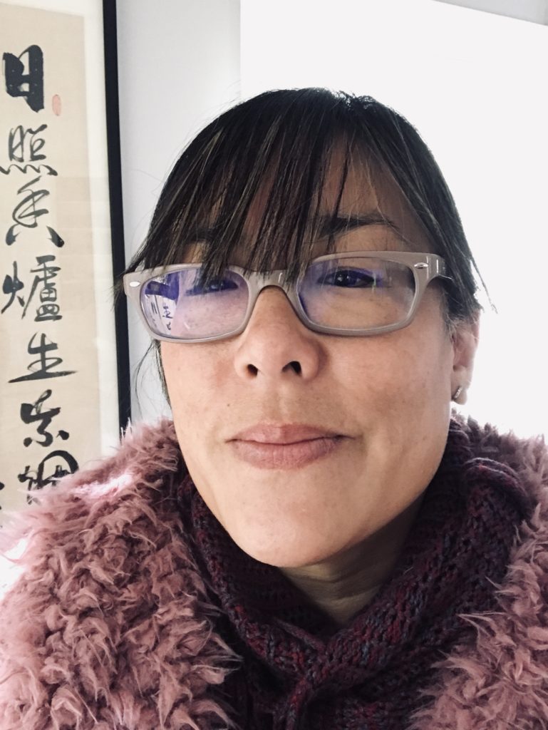 A selfie of Carleen. She is wearing beige glasses and a fluffy mauve-purple scarf.