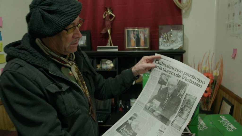 Valente (from American Exile) is holding up a newspaper that says, in Spanish, that a man from Chihuahua (him) participated in the Vietnam War. 
